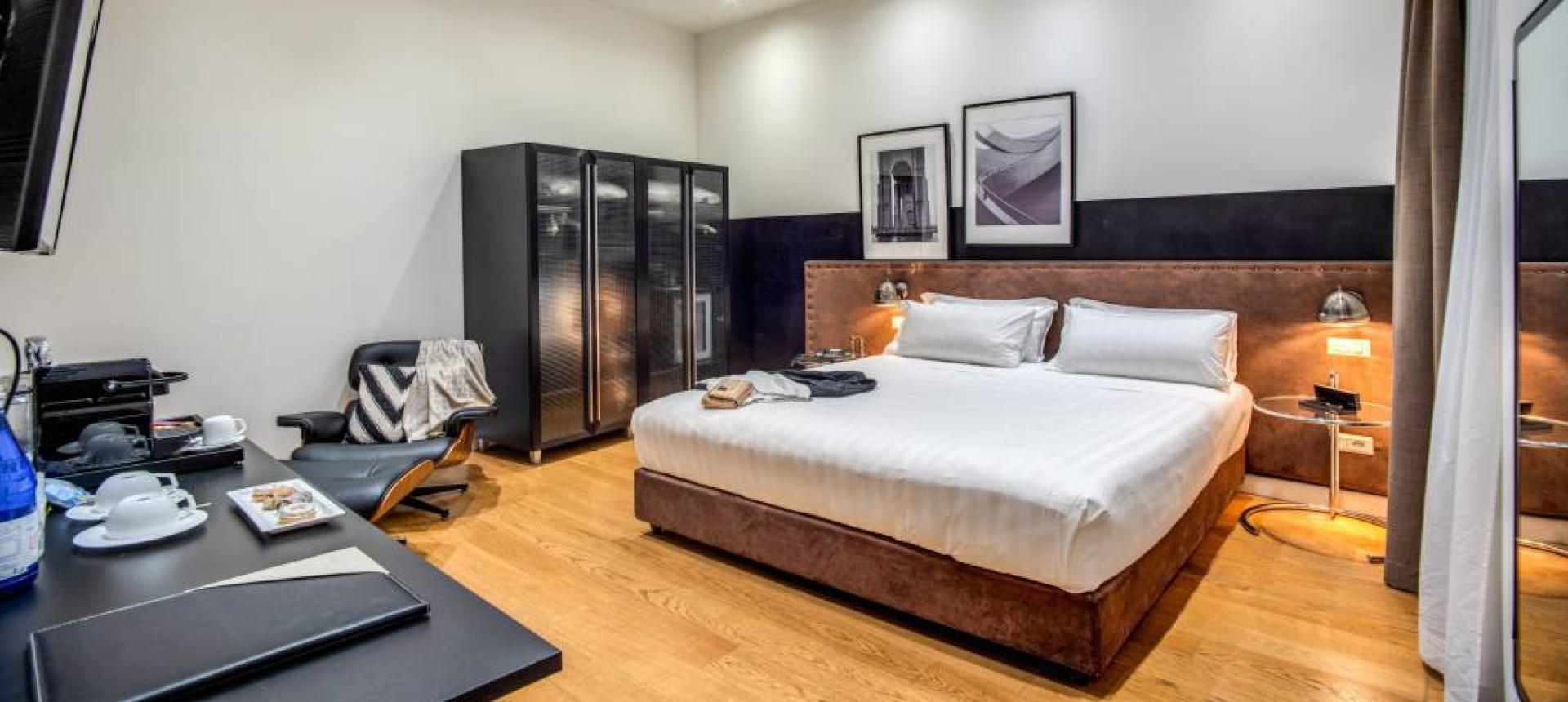Camera moderna con letto matrimoniale, armadio nero e arredamento elegante.