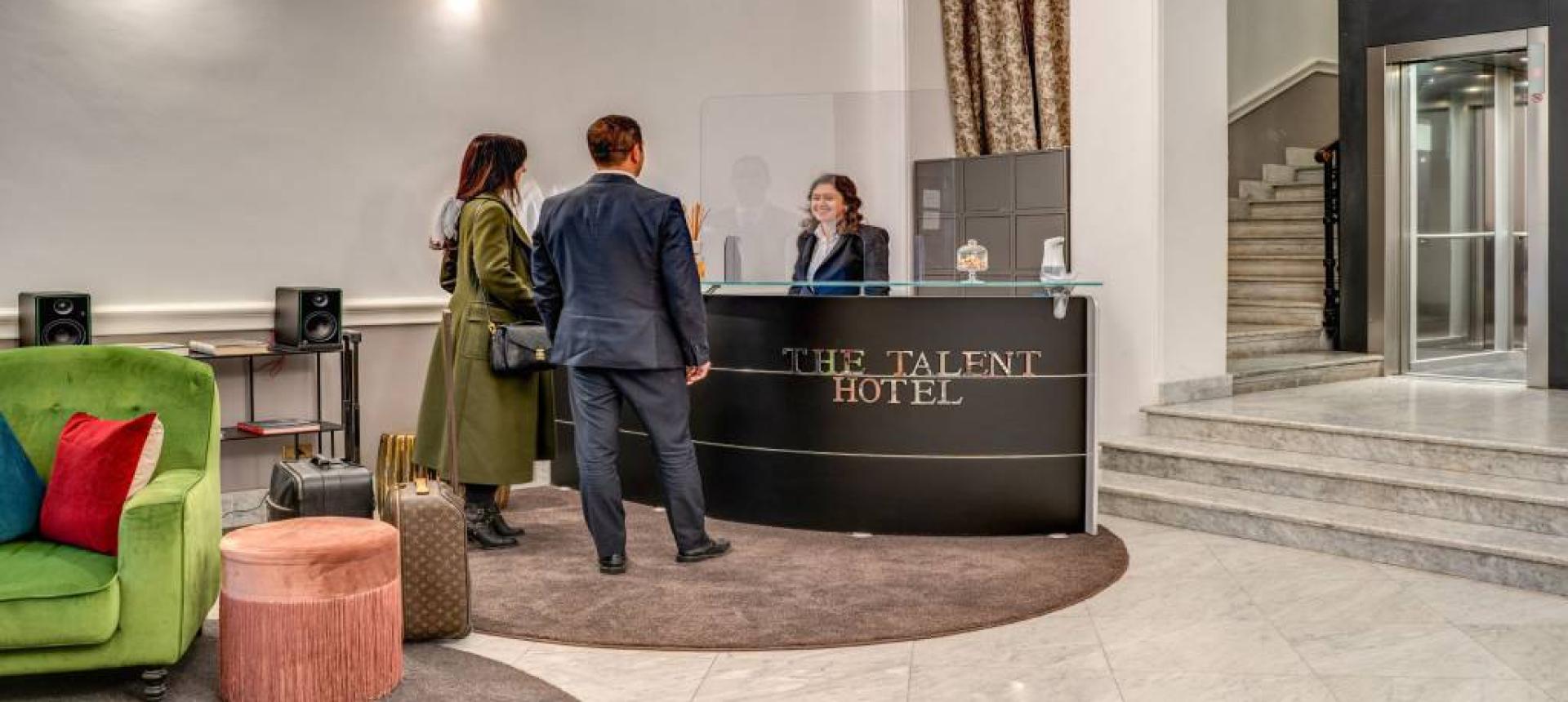 Reception moderna di un hotel con clienti e arredamento elegante.