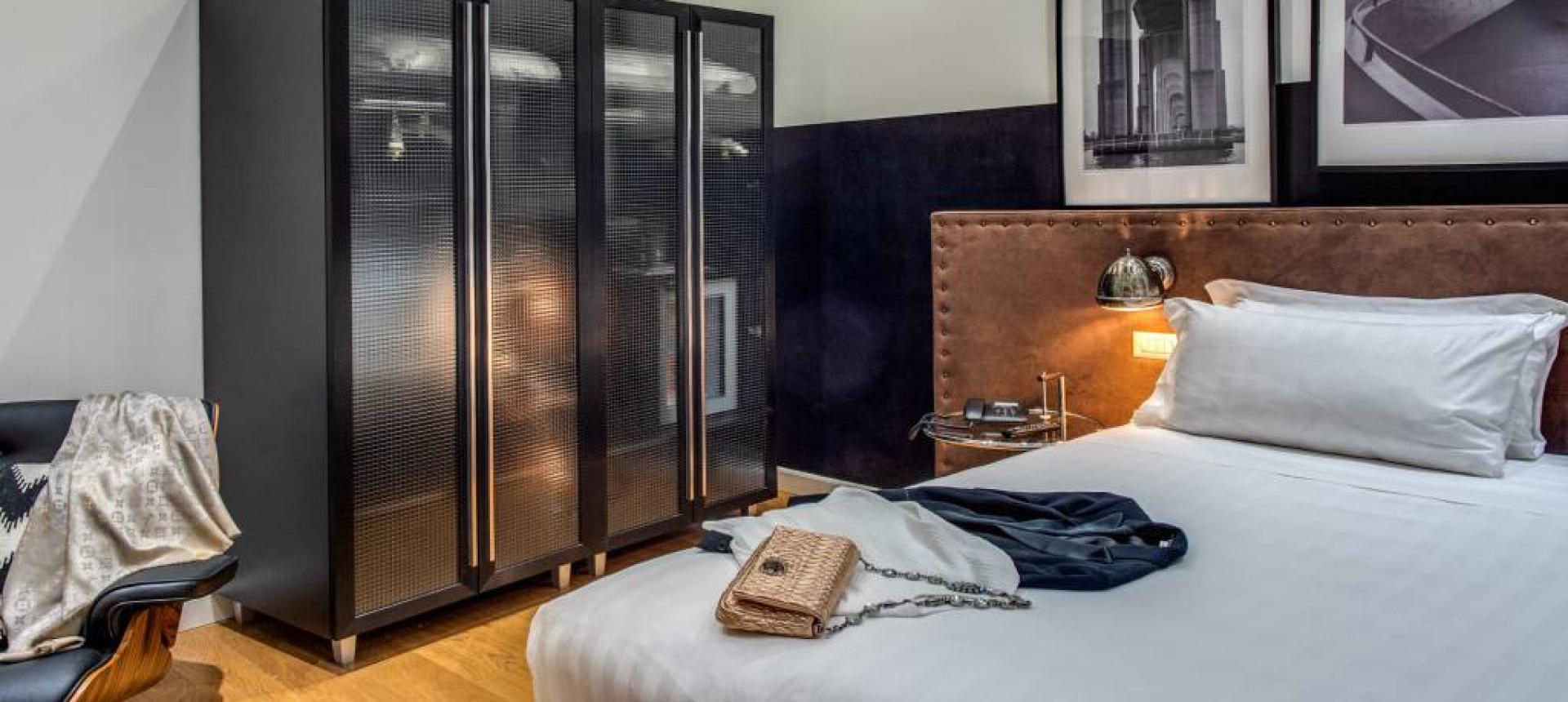 Camera moderna con letto, armadio nero e fotografie artistiche alle pareti.