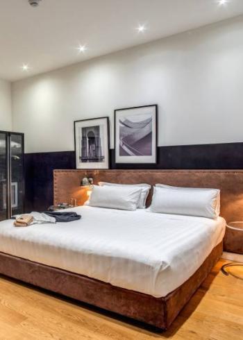 Camera moderna con letto matrimoniale, arredi eleganti e illuminazione soffusa.
