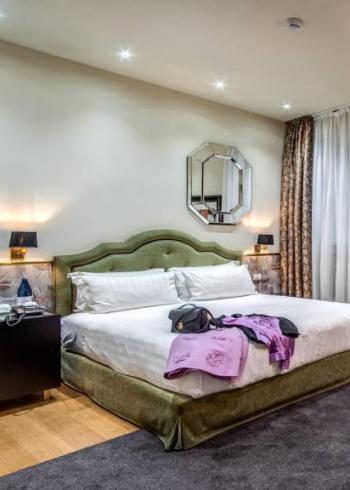 Camera elegante con letto matrimoniale, arredi moderni e illuminazione soffusa.