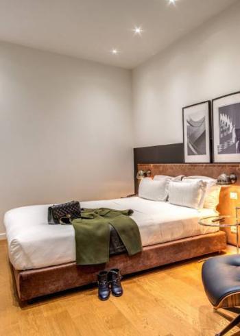Camera moderna con letto, poltrona, decorazioni minimaliste e pavimento in legno.