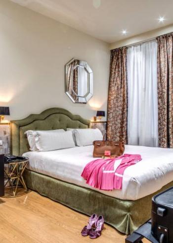 Camera d'albergo elegante con letto matrimoniale, valigia e decorazioni moderne.