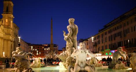Fontana a Piazza Navona di notte, con statue illuminate e sfondo di edifici storici.