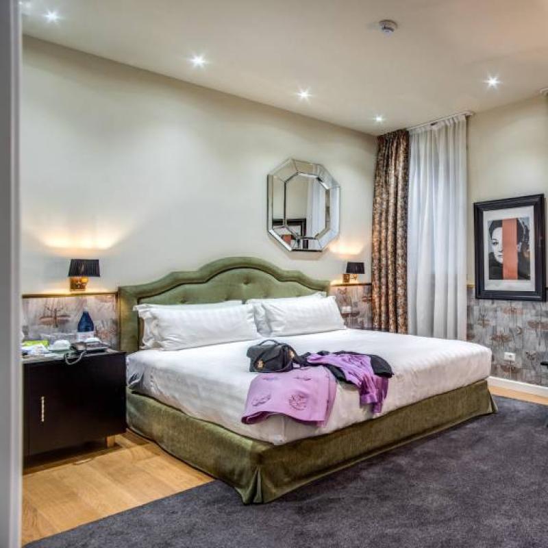 Camera elegante con letto matrimoniale, illuminazione soffusa e arredamento moderno.