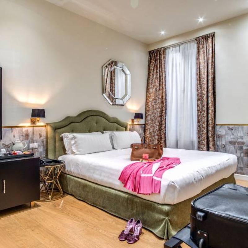 Camera d'hotel accogliente con letto, valigia e decorazioni eleganti.