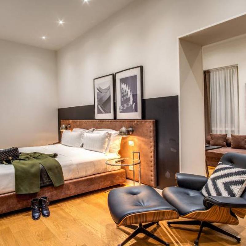 Camera moderna con letto, poltrona elegante, pavimento in legno e decorazioni artistiche.