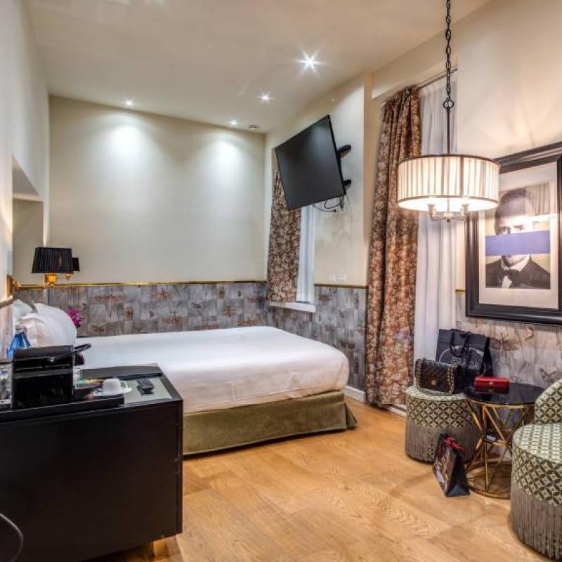 Camera moderna con letto matrimoniale, TV a parete e arredi eleganti.