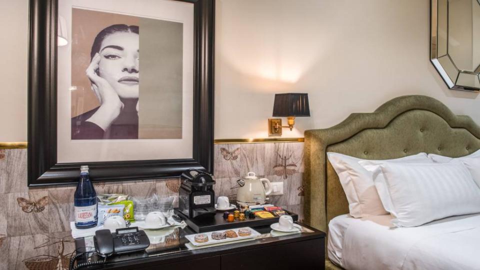 Camera d'hotel elegante con macchina da caffè, acqua e ritratto artistico.