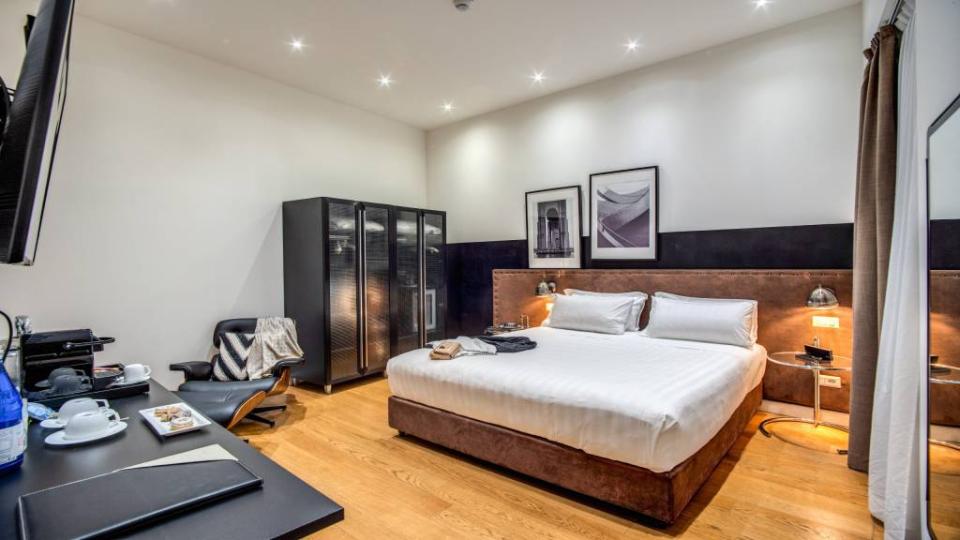 Camera moderna con letto matrimoniale, armadio scuro e scrivania con bevande.