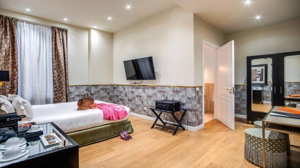 Camera d'hotel elegante con letto, TV a parete e arredamento accogliente.