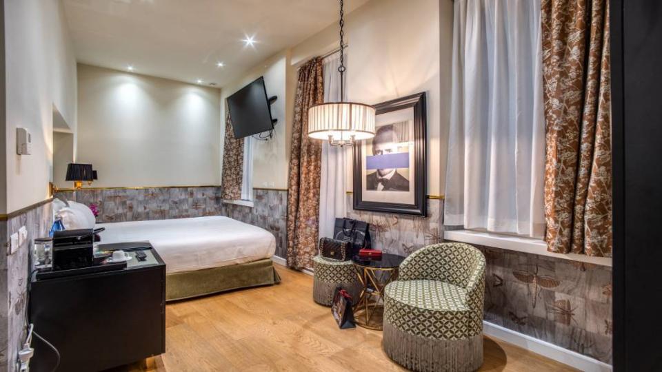 Camera moderna con letto, TV, sedie e decorazioni eleganti.